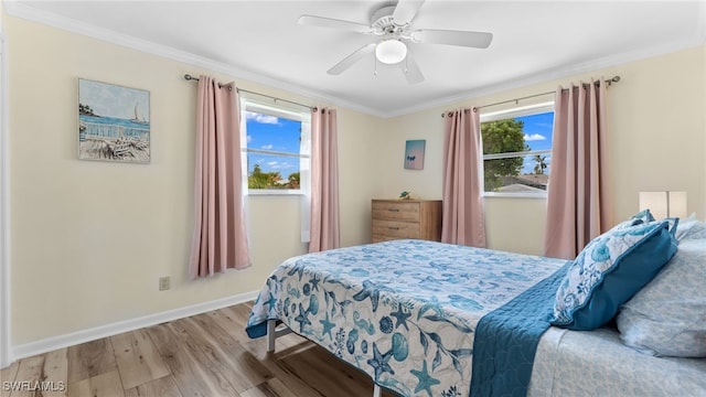 bedroom featuring light hardwood / wood-style floors, multiple windows, ornamental molding, and ceiling fan