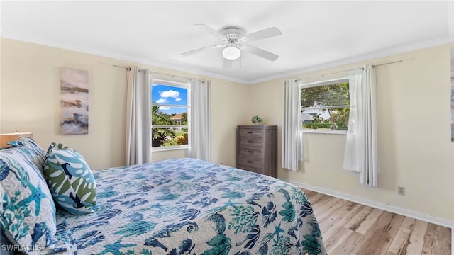 bedroom with ceiling fan, crown molding, multiple windows, and light hardwood / wood-style floors