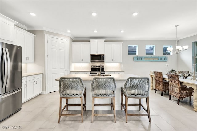 kitchen with appliances with stainless steel finishes, white cabinetry, sink, and an island with sink