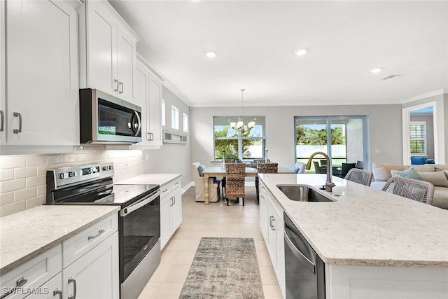 kitchen featuring a healthy amount of sunlight, stainless steel appliances, sink, and an island with sink