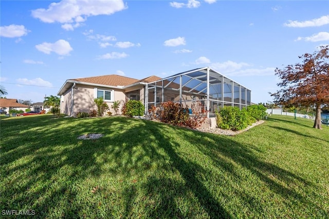 rear view of house featuring glass enclosure and a yard