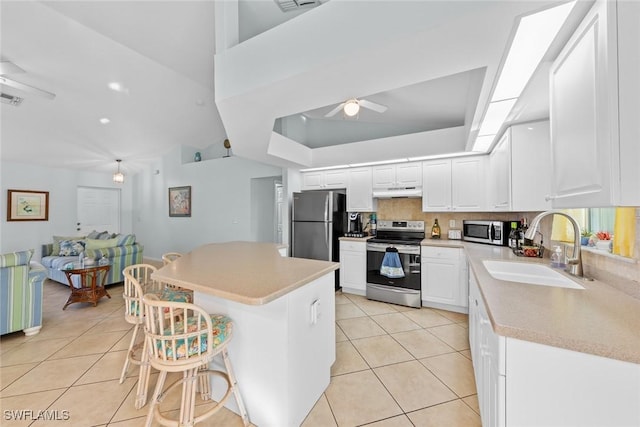 kitchen featuring white cabinets, appliances with stainless steel finishes, a kitchen bar, sink, and backsplash