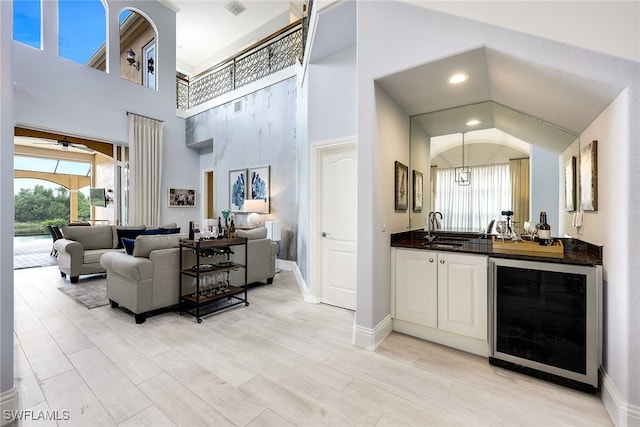 bar featuring sink, ceiling fan, beverage cooler, light hardwood / wood-style flooring, and pendant lighting