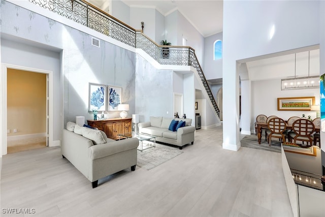 living room with a high ceiling, light hardwood / wood-style floors, and a notable chandelier