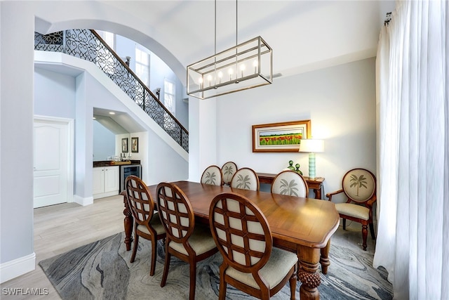 dining area featuring an inviting chandelier, beverage cooler, vaulted ceiling, and light hardwood / wood-style floors