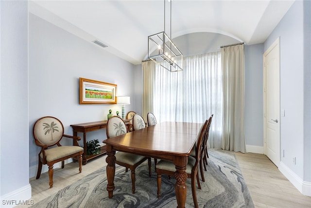 dining area featuring lofted ceiling, an inviting chandelier, and light hardwood / wood-style flooring