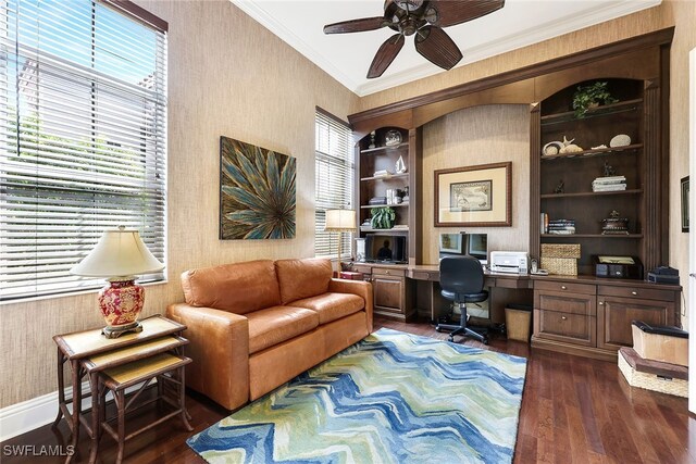 home office featuring built in shelves, ornamental molding, dark hardwood / wood-style floors, ceiling fan, and built in desk