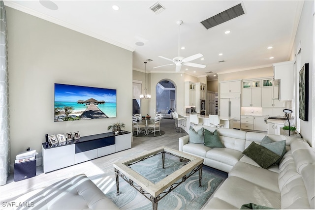 living room featuring ceiling fan with notable chandelier, light wood-type flooring, and ornamental molding