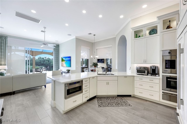 kitchen with sink, ornamental molding, white cabinetry, light hardwood / wood-style flooring, and decorative light fixtures