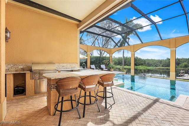 view of pool with glass enclosure, an outdoor wet bar, a patio area, a water view, and area for grilling