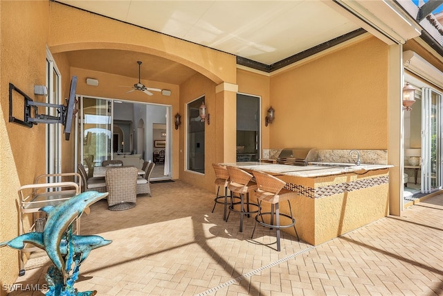 view of patio / terrace featuring ceiling fan, an outdoor bar, a grill, and exterior kitchen