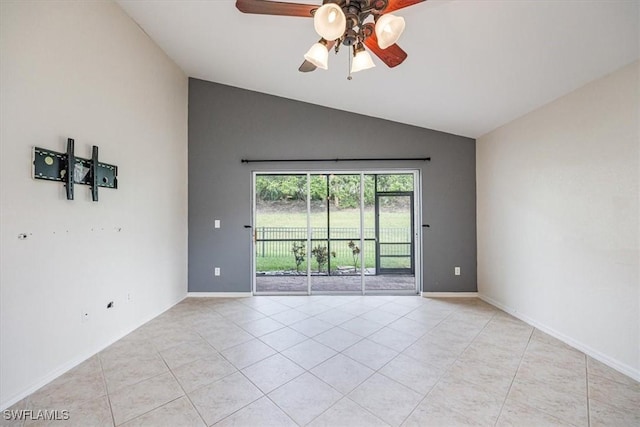 empty room with ceiling fan, vaulted ceiling, and light tile patterned floors