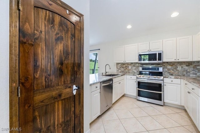 kitchen with stainless steel appliances, white cabinetry, tasteful backsplash, and light stone counters