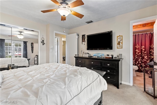 carpeted bedroom with ceiling fan, ensuite bath, a closet, and a textured ceiling