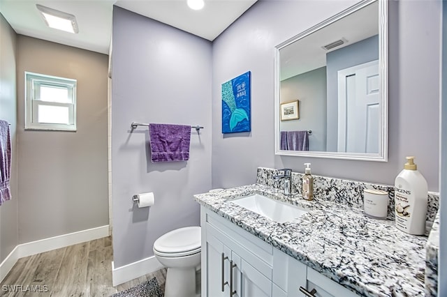 bathroom with vanity, toilet, and hardwood / wood-style floors