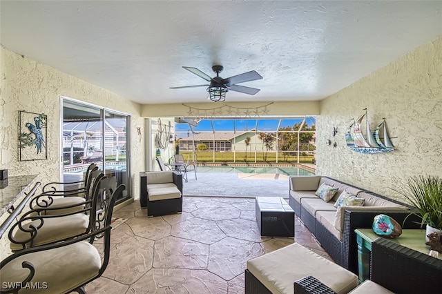 view of patio featuring an outdoor living space, glass enclosure, and ceiling fan