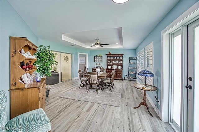 dining room with ceiling fan, a raised ceiling, and hardwood / wood-style floors