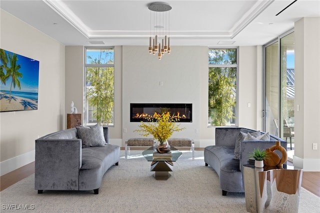 living room featuring an inviting chandelier, light hardwood / wood-style flooring, floor to ceiling windows, and a tray ceiling