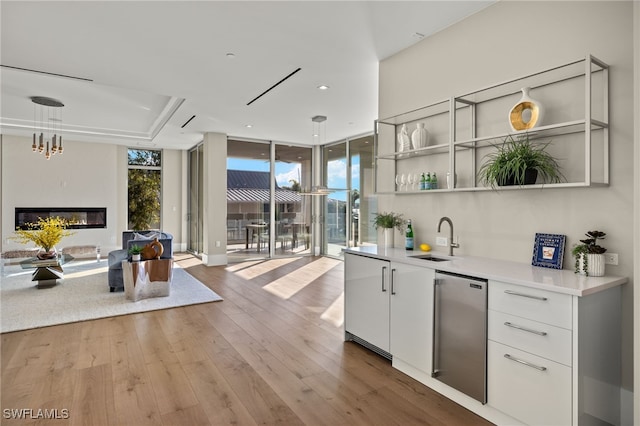 kitchen featuring white cabinets, hanging light fixtures, light hardwood / wood-style flooring, stainless steel fridge, and a wall of windows