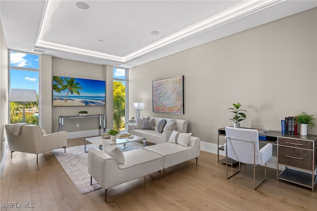 living room featuring a tray ceiling, light hardwood / wood-style flooring, and floor to ceiling windows