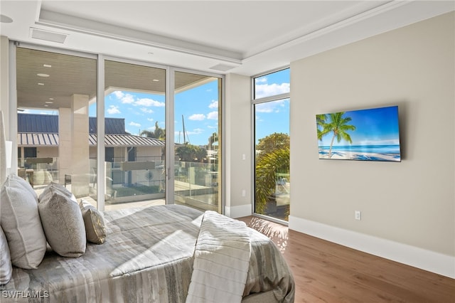 bedroom with hardwood / wood-style flooring, a wall of windows, access to outside, and multiple windows