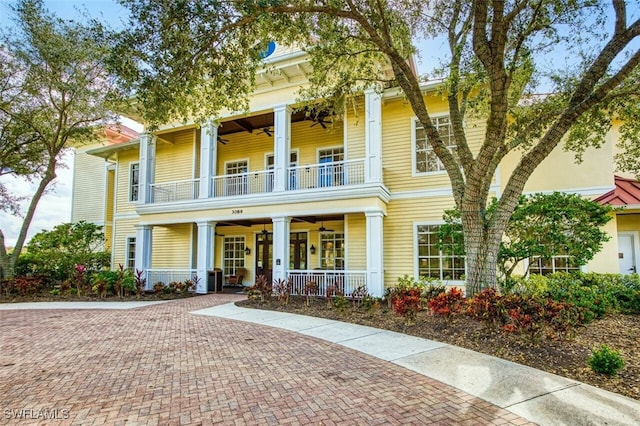 greek revival inspired property with ceiling fan, covered porch, and a balcony