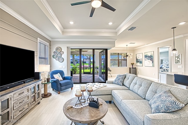 living room with ornamental molding, a tray ceiling, and ceiling fan with notable chandelier