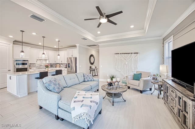 living room featuring ornamental molding, light tile patterned floors, a tray ceiling, and ceiling fan