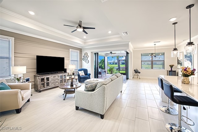 living room featuring crown molding, a tray ceiling, and ceiling fan