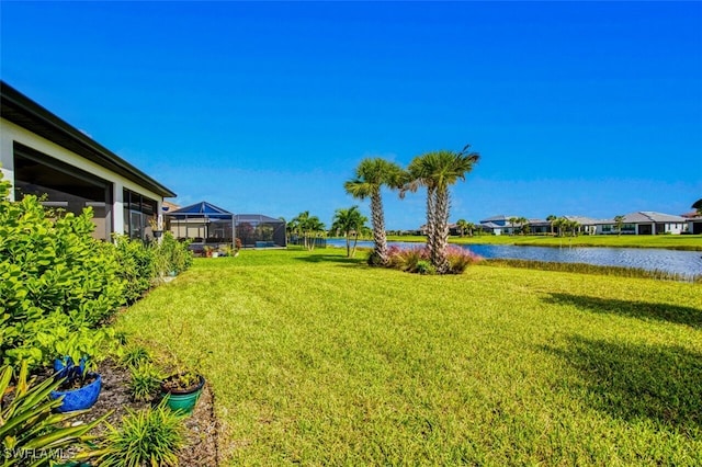 view of yard featuring a water view and glass enclosure