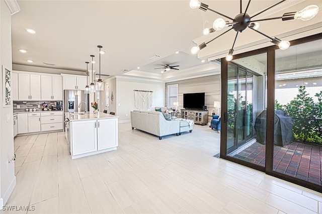 kitchen featuring sink, an island with sink, decorative light fixtures, white cabinets, and decorative backsplash