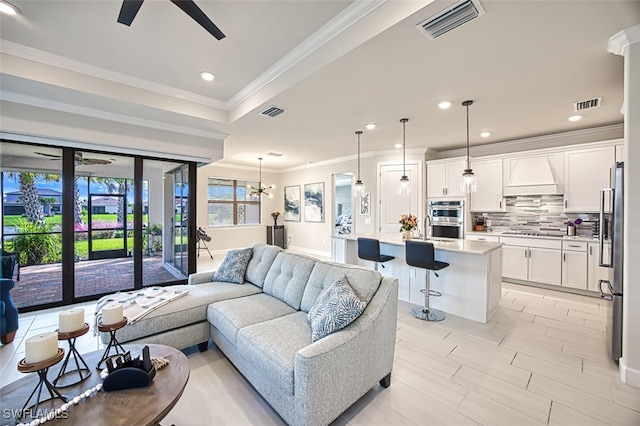 living room with crown molding and ceiling fan with notable chandelier