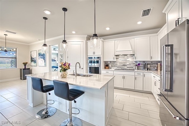 kitchen with premium range hood, white cabinets, stainless steel appliances, and sink