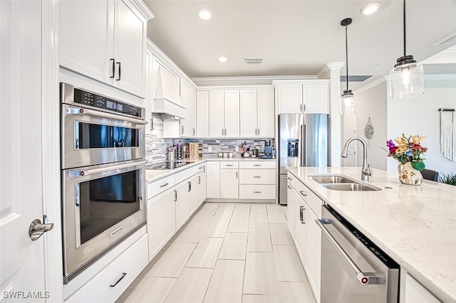 kitchen with appliances with stainless steel finishes, sink, hanging light fixtures, white cabinetry, and light stone counters