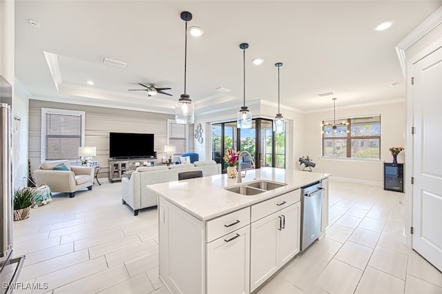 kitchen with white cabinets, an island with sink, stainless steel dishwasher, decorative light fixtures, and sink