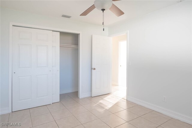 unfurnished bedroom with light tile patterned floors, a closet, and ceiling fan