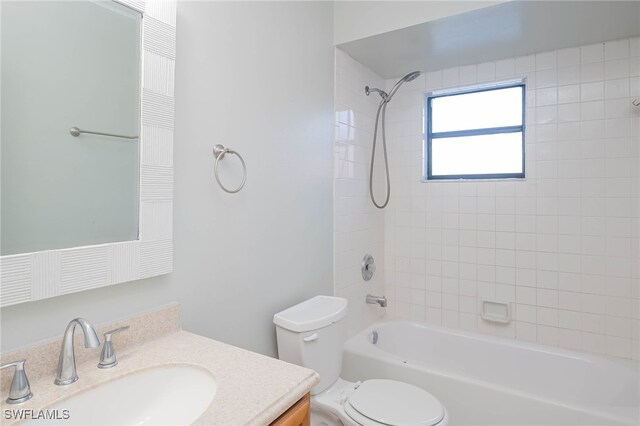 full bathroom with tiled shower / bath, vanity, and toilet