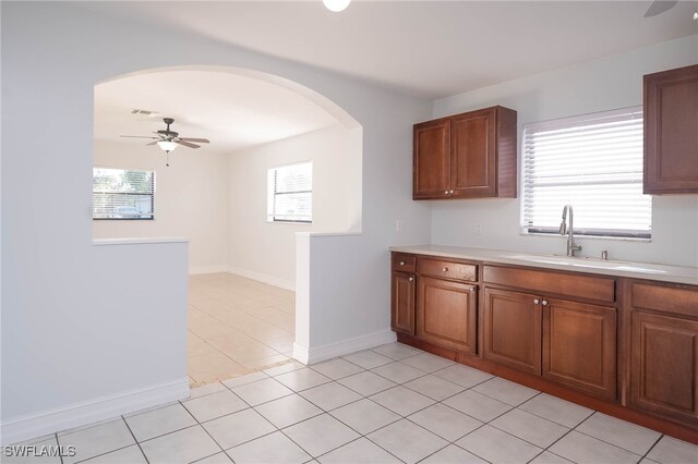 kitchen featuring ceiling fan, sink, light tile patterned floors, and a healthy amount of sunlight