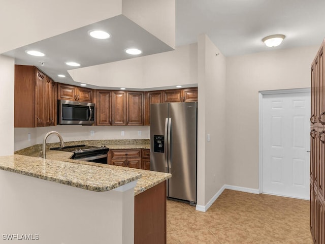 kitchen featuring light stone counters, stainless steel appliances, and kitchen peninsula