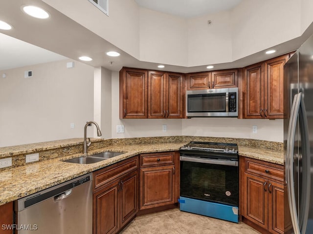 kitchen with kitchen peninsula, light stone counters, appliances with stainless steel finishes, light tile patterned flooring, and sink