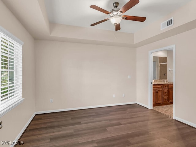 empty room with hardwood / wood-style floors, a tray ceiling, and ceiling fan