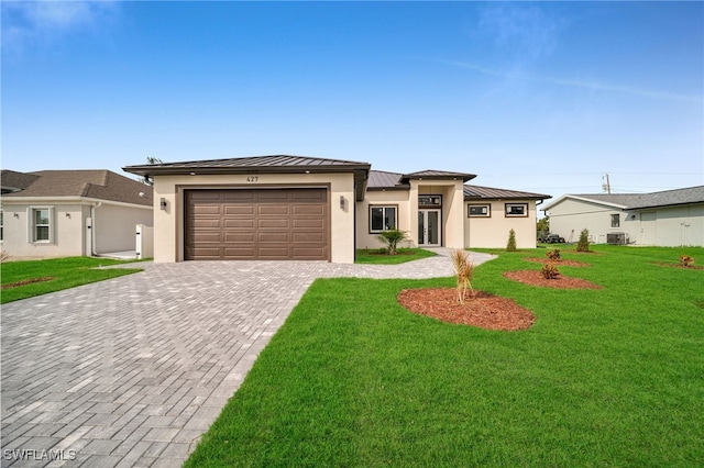 view of front of property with a front lawn, central AC unit, and a garage