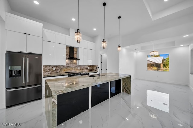 kitchen featuring appliances with stainless steel finishes, sink, white cabinetry, wall chimney exhaust hood, and pendant lighting