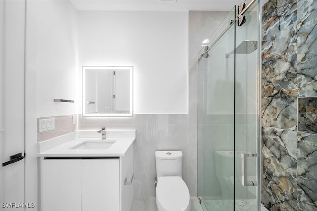 bathroom featuring tile walls, vanity, a shower with shower door, and toilet