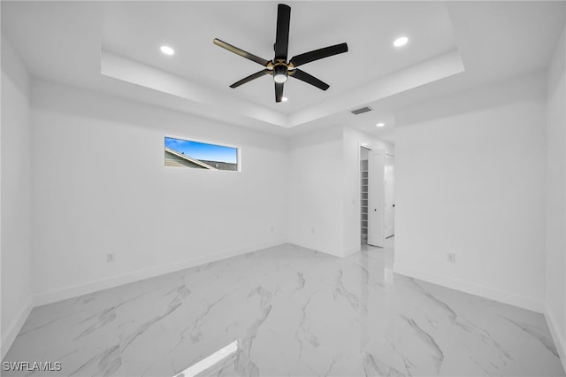 empty room featuring a tray ceiling and ceiling fan