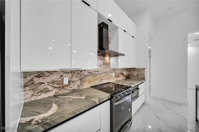 kitchen featuring tasteful backsplash, wall chimney range hood, appliances with stainless steel finishes, white cabinetry, and dark stone counters