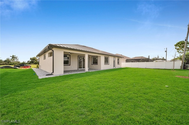 back of house with a patio and a lawn