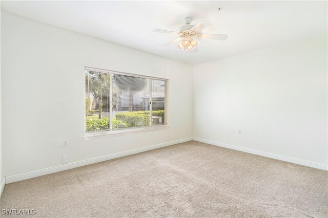 carpeted spare room featuring ceiling fan