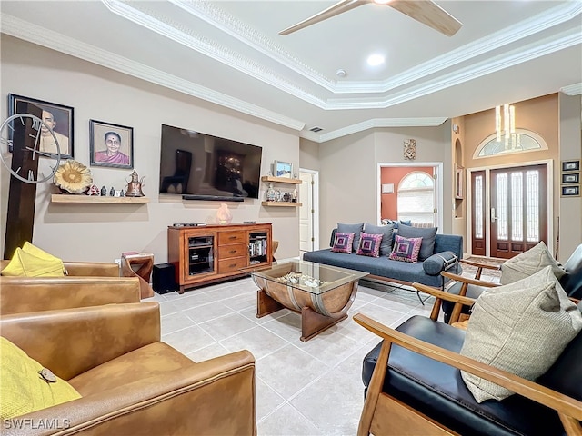 living area featuring visible vents, ornamental molding, a ceiling fan, a tray ceiling, and light tile patterned floors