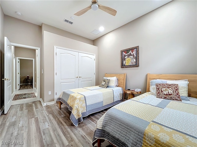 bedroom featuring visible vents, ceiling fan, baseboards, light wood-type flooring, and a closet
